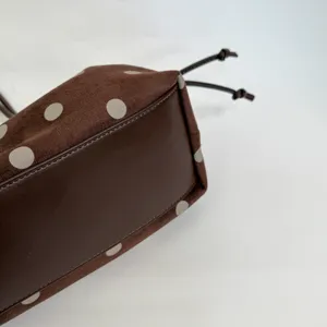 Close up detail view of brown polka dot suede bucket bag base and drawstring feature.