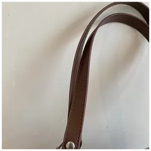 Brown leather bag strap detail shot, minimalist tote bag accessory, stylish daily commute.