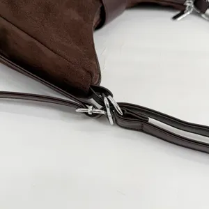 Brown suede handbag metal hardware detail, close-up view of the adjustable shoulder strap ring.