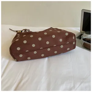 Detail view of a brown polka dot large capacity tote bag on white cloth with laptop prop.