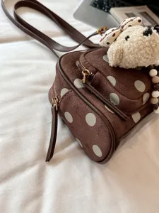 Détail de sac Boston à pois marron avec texture daim douce et charmant pendentif en peluche.