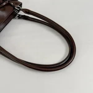 Dark brown leather shoulder bag handle detail, elegant underarm bag strap design.