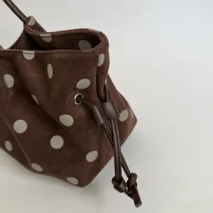 Brown polka dot pleated bucket bag detail showing soft suede material and drawstring closure.