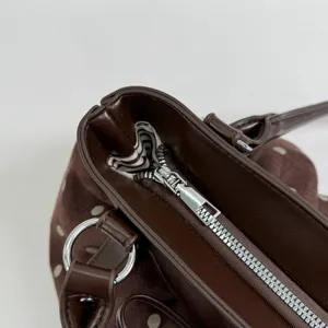Brown polka dot tote bag detail, featuring metal zipper, silver ring, and striped lining.
