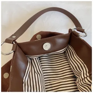 Brown leather shoulder bag interior detail showing striped lining and magnetic clasp.