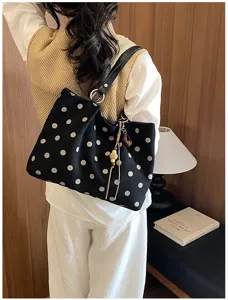 Detail shot of the stylish black and white polka dot canvas tote bag worn by a model.