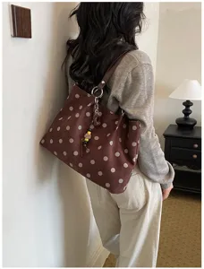 Detailed view of the brown polka dot tote bag worn on shoulder, lifestyle scene.
