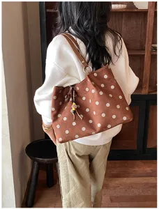 Detailed view of the brown polka dot tote bag worn on shoulder, showing capacity & style.