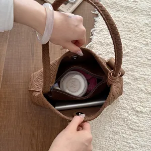 Detaillierte Draufsicht auf das Innere einer braunen geflochtenen Handtasche mit Stauraum.