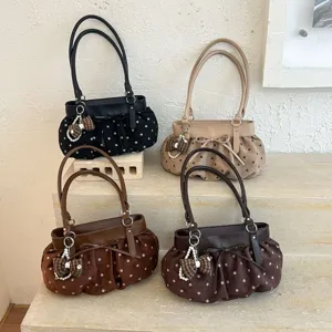 Detail view of fashionable polka dot shoulder bags with bows and pearl charms for daily commuting.