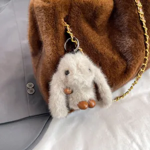 Primo piano dettagliato della borsa a tracolla in peluche soffice con ciondolo coniglio e catena.