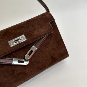 Detalle de bolso de ante marrón, con textura suave y elegante cierre de metal plateado.
