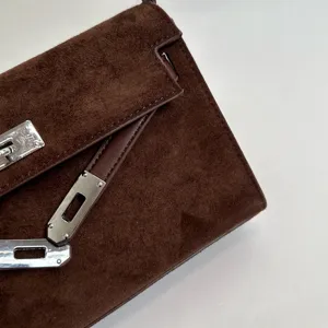 Primer plano detallado del bolso de ante marrón con textura suave y cierre de metal prémium.