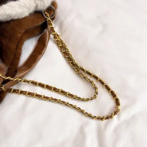 Primo piano dettagliato di borsa di lusso in peluche con tracolla a catena dorata.