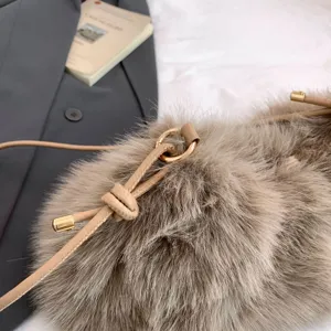 Plush bucket shoulder bag detail, fuzzy crossbody bag with drawstring and gold hardware.