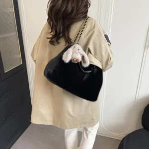 Dettaglio borsa a spalla in peluche nero con morbida pelliccia sintetica e ciondolo coniglio.