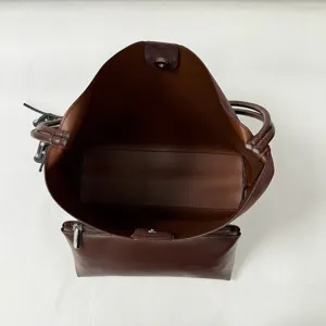 Brown leather bucket bag interior detail showing spacious compartment and attached pouch.