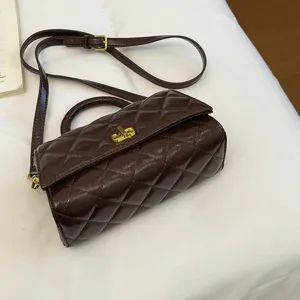 Vista dettagliata di una borsa a tracolla trapuntata marrone scuro con manico e dettagli dorati.