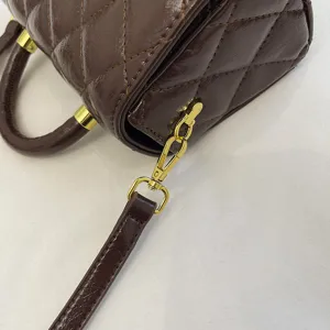 Dettaglio in primo piano della borsa in pelle trapuntata marrone con dettagli dorati.