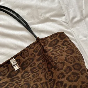 Close-up detail of a brown leopard print tote bag with black straps and silver hardware.