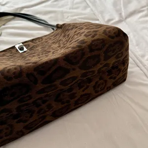 Leopard print tote bag detail view, showing soft faux suede texture and metal turn-lock closure.