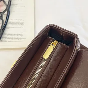 Vista dettagliata di borsa box in pelle matelassata marrone con zip dorata e cuciture fini.