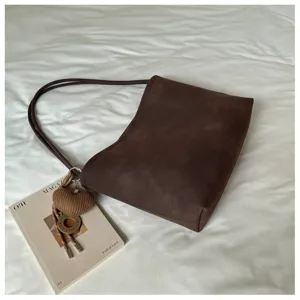 Detailed view of dark brown vintage suede shoulder bag with knit heart pendant, chic tote.