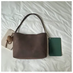 Detail shot of retro brown suede shoulder bag, large capacity commuter tote handbag style.