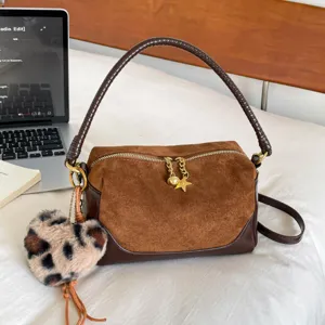 Brown suede pillow shoulder bag with braided handle, leopard heart charm, and spacious design.