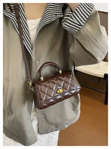 Dettaglio della borsa a tracolla matelassé in vernice retrò con chiusura chic e manico superiore.
