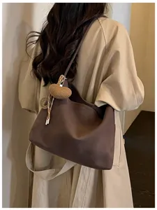 Detailed view of slouchy brown shoulder tote bag with knitted heart charm and minimalist style.