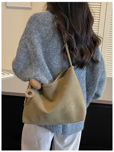 Detail view of the elegant olive green suede shoulder bag showcasing its stylish hobo design.