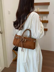 Vue détaillée d'un sac à bandoulière chic en suédine marron avec boucle et charm.