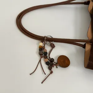 Schicker brauner Shopper Riemen Detail mit Holzperlen und Herz Anhänger Dekoration.