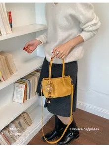Detailed view of the yellow suede tote bag with flower pendant and shoulder strap.