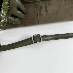 Gros plan détaillé d'un sac à main en suède vert olive avec boucle en métal et nœud élégant.