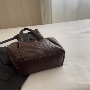 Detailed view of the dark brown woven leather tote bag, showcasing fine texture and craftsmanship.