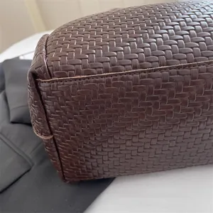 Close-up detail of dark brown woven leather bag showing intricate handcrafted leather pattern texture