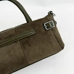 Gros plan d'un sac à main en suède vert olive, garniture en cuir et boucle en métal.