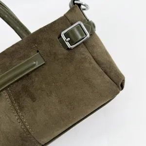 Détail de sac à main en daim vert avec lanière à boucle métallique, élégant et chic.