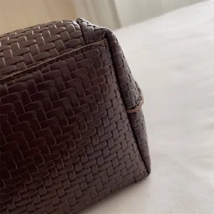 Dark brown woven leather bag detail close-up showing premium texture and craftsmanship