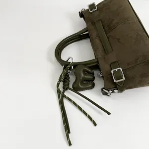 Sac à main en daim vert olive avec boucle en métal et pendentif. Élégant sac porté épaule.