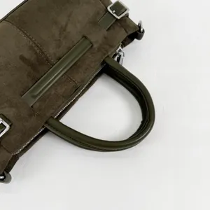 Détail de sac à main en daim vert olive, élégante poignée en cuir, boucle en métal.