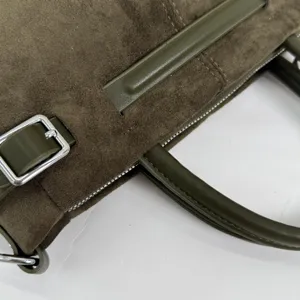 Gros plan sur les détails du sac à main en daim vert olive avec bordure en cuir et boucle.