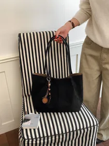 Schwarze Wildleder-Tasche Detail zeigt weiche Textur, geräumige Kapazität und edlen Anhänger.
