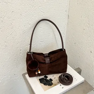 Bruine suède schoudertas voor dames met pluche pompon-hanger en afneembare crossbody riem.