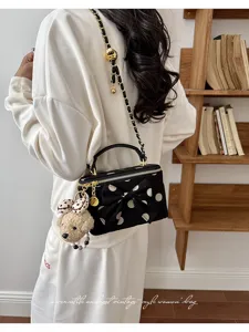 Chic black polka dot crossbody bag with bow, stylish chain strap and cute bear pendant.