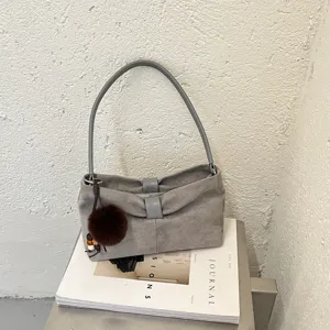 Minimalistische grijze suède schoudertas met chique handvat en schattige pompon hanger.