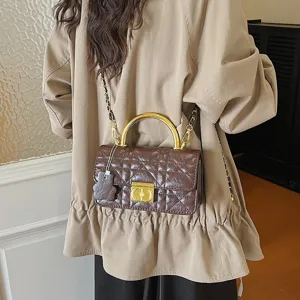 Detailansicht der braunen gesteppten Ledertasche mit Metallgriff und feiner Kette.