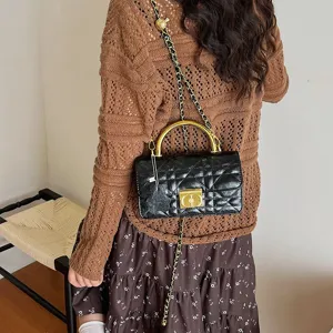 Nahaufnahme einer schwarzen gesteppten Kettenhandtasche mit Goldgriff im Retro-Stil.